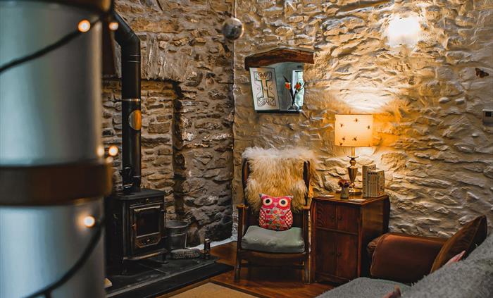 Hen Ffermdy cottage living area with armchair beside the wood burning stove